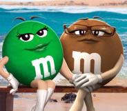 The green M&M (left) sitting on a bench on the beach with her lesbian partner, the brown M&M