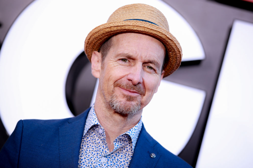 Denis O'Hare in a blue jacket and shirt, and a wicker hat