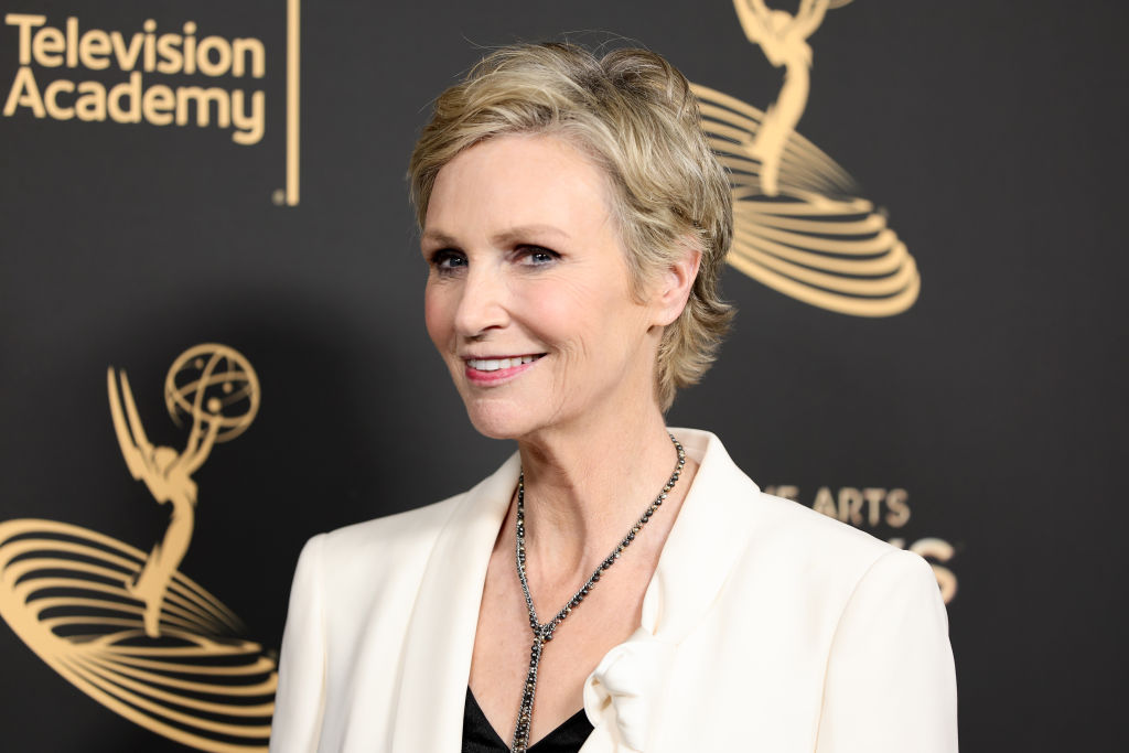 Jane Lynch in a white jacket and silver necklace