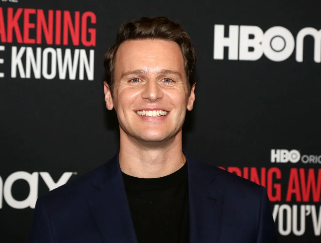Jonathan Groff in a black t-shirt and navy blue jacket