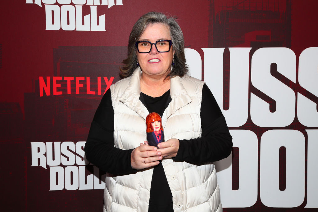 Rosie O'Donnell in a black long-sleeved shirt and white puffer jacket