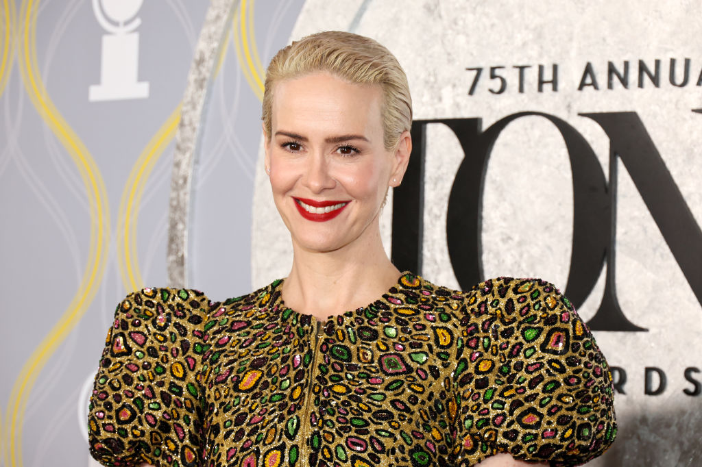 Sarah Paulson with cropped blonde hair wearing a gold dress with metallic sequin details