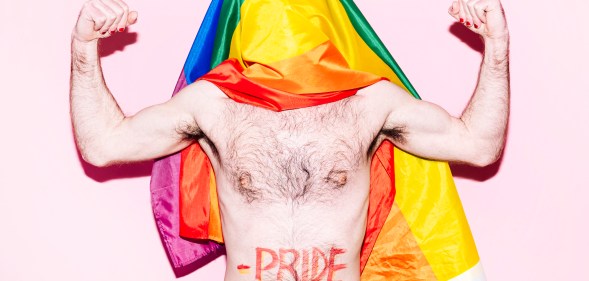A gay otter flexing his arms with a Pride flag draped over his head