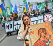 A Romanian woman holds an Orthodox icon as she marches with Romanian flag during a protest against incoming Gay Pride in Bucharest on June 8, 2013.