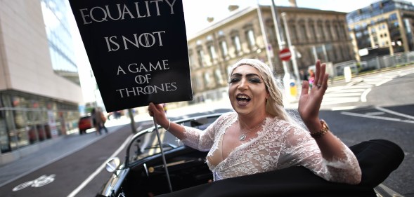 A drag queen hlding a sign saying "Equality is not a game of thrones" takes part in Belfast's gay pride protesting Northern Ireland's ban on same sex marriage.