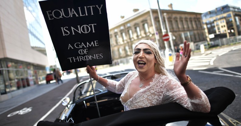 A drag queen hlding a sign saying "Equality is not a game of thrones" takes part in Belfast's gay pride protesting Northern Ireland's ban on same sex marriage.