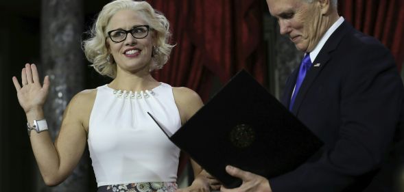 US Senator from Arizona Kirsten Sinema holds a law book as she is sworn in by Vice President Mike Pence on January 3, 2019.
