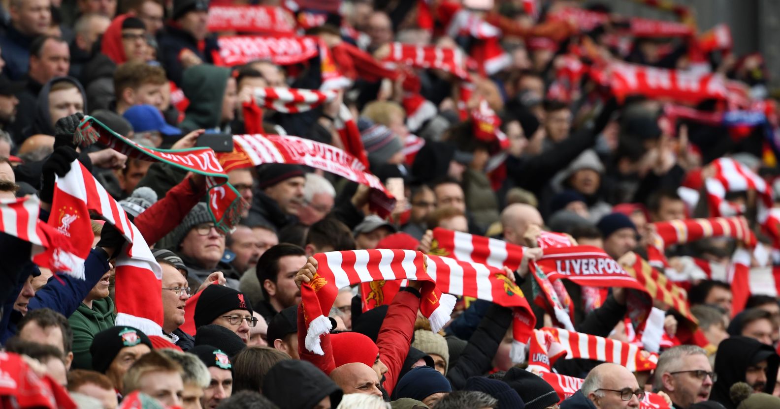 Liverpool supporters hold up their scarves in the crowd ahead of the English Premier League football match between Liverpool and Chelsea at Anfield in Liverpool, north west England on April 14, 2019.