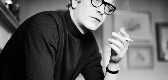 English actor Michael Caine smoking a cigarette.