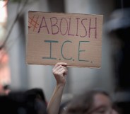 A hand holding an 'abolish ice' placard