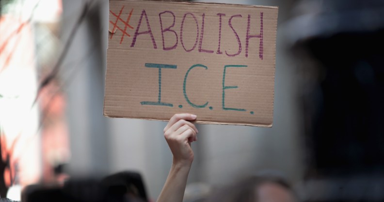 A hand holding an 'abolish ice' placard