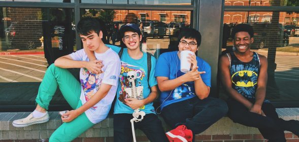 Four teenage boys sitting on a wall