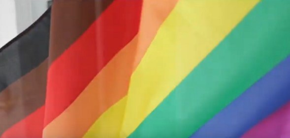 A still of Manchester Pride's promotional video, featuring an eight-striped Pride flag