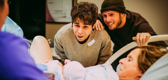 Matthew Eledge and husband Elliot Dougherty look on as Cecile Reynek Eledge holds newborn Uma Louise Dougherty-Eledge.