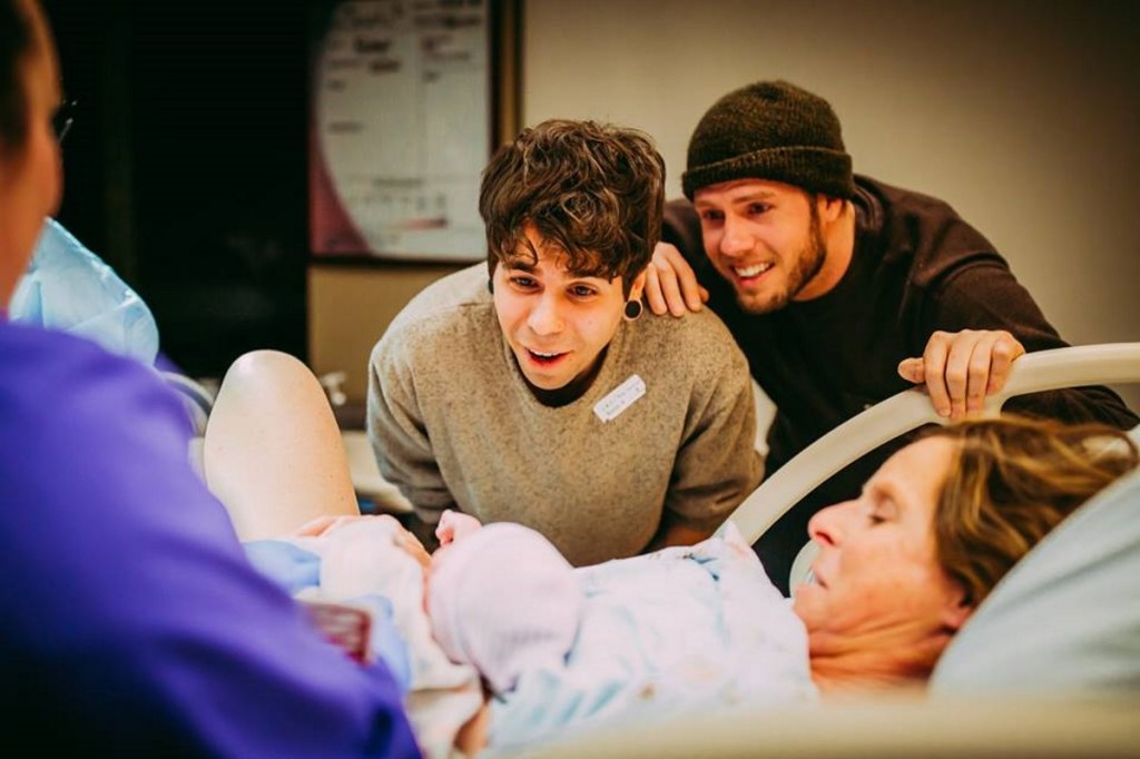 Matthew Eledge and husband Elliot Dougherty look on as Cecile Reynek Eledge holds newborn Uma Louise Dougherty-Eledge.