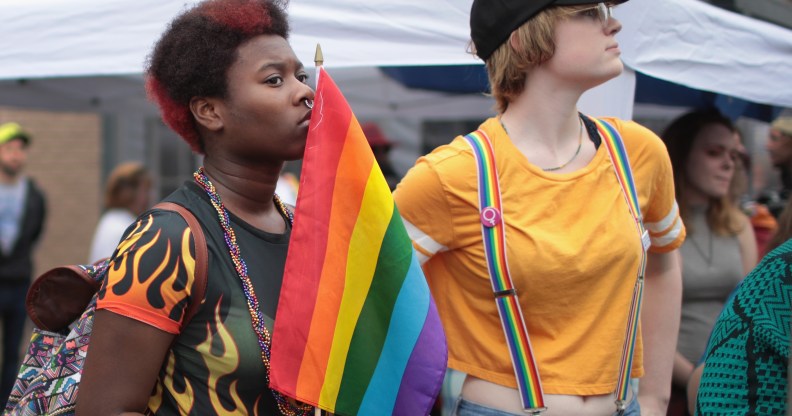 A black woman holding a rainbow flag next to a white woman wearing rainbow braces
