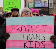 A woman holding a sign which says "protect trans kids"