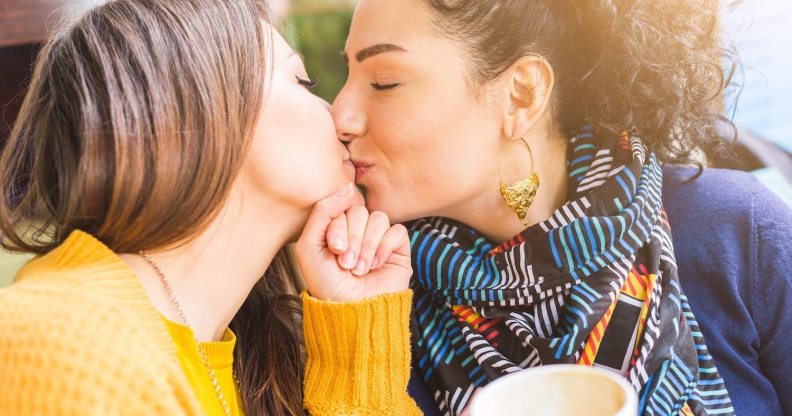 Lesbian couple kissing at a cafe