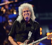 Brian May holds his guitar while on stage