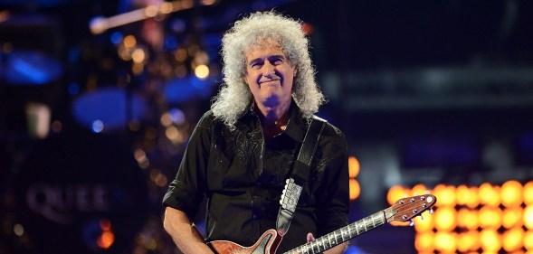 Brian May holds his guitar while on stage