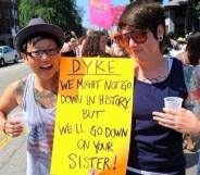 Two women holding a sign that reads 'dyke'
