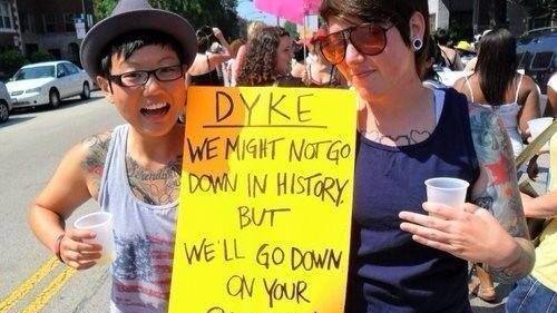 Two women holding a sign that reads 'dyke'