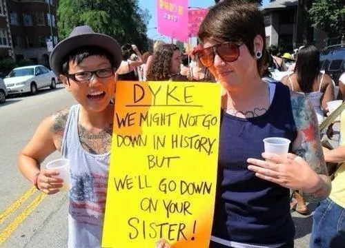 Two women holding a sign that reads 'dyke'