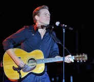 Bryan Adams playing the guitar on stage
