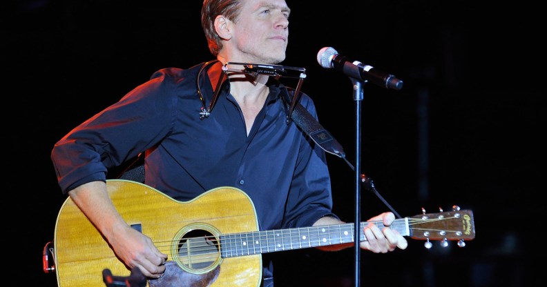 Bryan Adams playing the guitar on stage