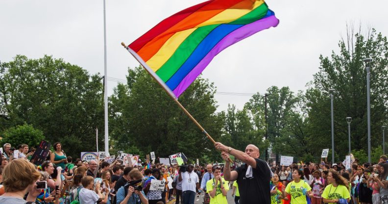 Principal Pete Cahall, waves a rainbow flag, symbolizing gay pride, at a rally of about 1000 Woodrow Wilson High School students and gay supporters June 9, 2014 at Woodrow Wilson High School in Washington, DC. The rally was held to counter a planned protest by Westboro Baptist Church, the Kansas-based organization known for anti-gay picketing at funerals. AFP PHOTO/Paul J. Richards (Photo credit should read PAUL J. RICHARDS/AFP/Getty Images)