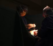 Two surgeons operate on someone in a dark room