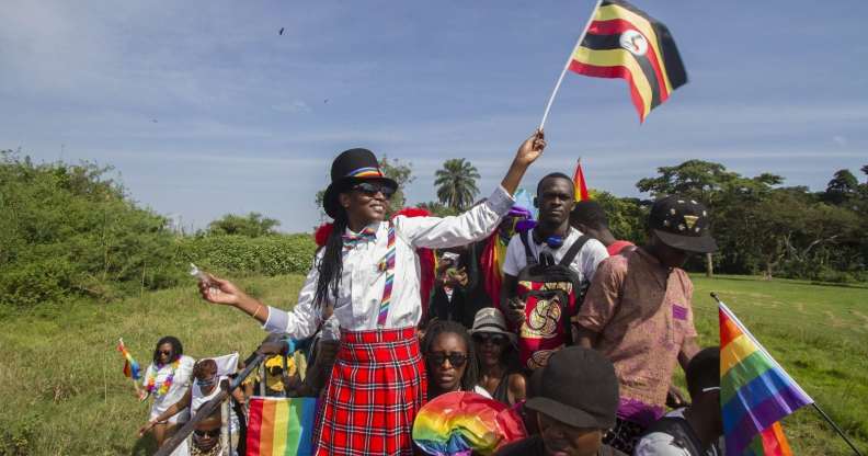 People waving Ugandan and rainbow flags take part in the Gay Pride parade in Entebbe on August 8, 2015. Ugandan activists gathered for a gay pride rally, celebrating one year since the overturning of a strict anti-homosexuality law but fearing more tough legislation may be on its way. Homosexuality remains illegal in Uganda, punishable by a jail sentence. AFP PHOTO/ ISAAC KASAMANI (Photo credit should read ISAAC KASAMANI/AFP/Getty Images)