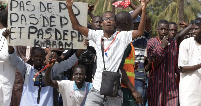 A protestor gestures on January 22, 2015 in Dakar during a demonstration against homosexuality. Under Senegalese law, anyone convicted of an "improper or unnatural act with a person of the same sex" faces up to five years in jail. The government has repeatedly ruled out legalising homosexuality in the deeply conservative Muslim-majority country. Banner reads "No fag". / AFP / SEYLLOU (Photo credit should read SEYLLOU/AFP/Getty Images)