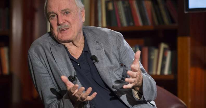 A screenshot of John Cleese sitting in a chair