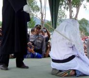 TAKENGON, INDONESIA: An Acehnese executor flogs a convicted woman in Takengon, in Indonesian central Aceh province, 19 August 2005 after an Islamic sharia court ordered four women to be flogged for petty gambling offences. The public lashing was the second since the Indonesian government allowed the western province to implement religious law as part of broader autonomy granted in 2001 to curb a separatist Islamist insurgency. AFP PHOTO (Photo credit should read STR/AFP/Getty Images)