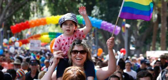 A woman carrying a child on her shoulder waves a rainbow flag during the opening event of the annual Gay Pride parade in the Israeli city of Tel Aviv, on June 3, 2016. (JACK GUEZ/AFP/Getty)