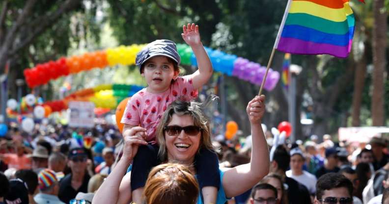 A woman carrying a child on her shoulder waves a rainbow flag during the opening event of the annual Gay Pride parade in the Israeli city of Tel Aviv, on June 3, 2016. (JACK GUEZ/AFP/Getty)