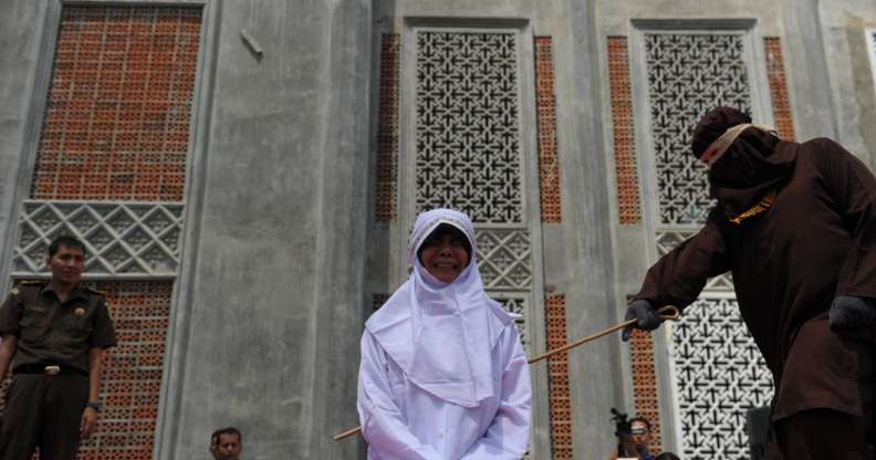 TOPSHOT - A religious officer canes an Acehnese youth onstage as punishment for dating outside of marriage, which is against sharia law, outside a mosque in Banda Aceh on August 1, 2016. The strictly Muslim province, Aceh has become increasingly conservative in recent years and is the only one in Indonesia implementing Sharia law. / AFP / CHAIDEER MAHYUDDIN (Photo credit should read CHAIDEER MAHYUDDIN/AFP/Getty Images)