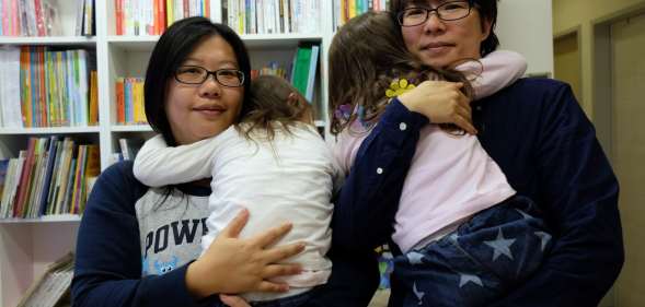 Same-sex couple Hope Chen (L), 37, and Zoro Wen, 34, pose with their twin daughters at their home in Taoyuan, northern Taiwan
