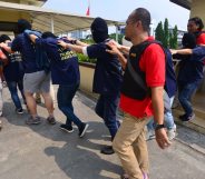 Indonesian police guard men arrested in a recent raid during a press conference at a police station in Jakarta on May 22, 2017. Indonesian police have detained 141 men who were allegedly holding a gay party at a sauna, an official said on May 22, the latest sign of a backlash against homosexuals in the Muslim-majority country
