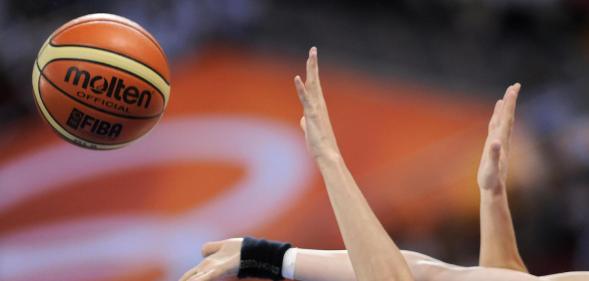 Women's hands grasping at a basketball