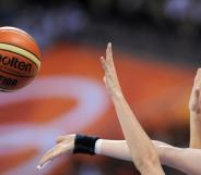 Women's hands grasping at a basketball