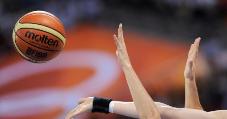 Women's hands grasping at a basketball