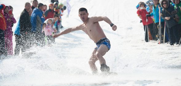 HARBIN, CHINA - MARCH 24: A man strip to the waist during the Naked Pig Skiing Carnival at the Yabuli Ski Resort on March 24, 2018 in Harbin of Heilongjiang Province, northeast China. Men stripped to the waist and women wearing swim suits attended the carnival which is held to promote skiing. (Photo by Tao Zhang/Getty Images)