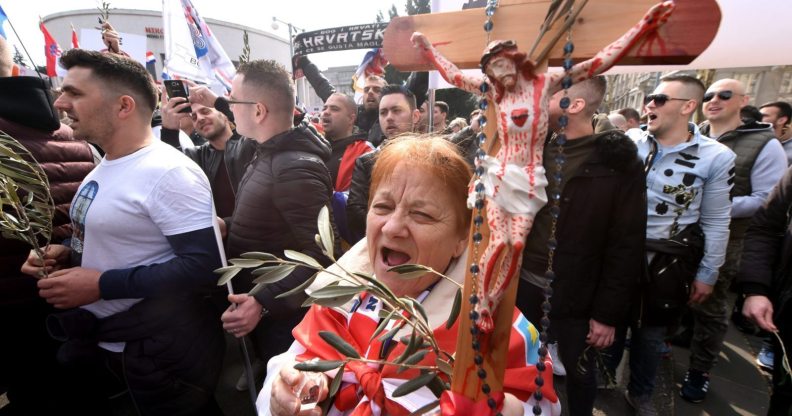 A woman holds a cross as opponents to a treaty safeguarding women, backed by the Roman Catholic Church, protest against its ratification arguing it is imposing what they call a "gender ideology in the Croatian capital, Zagreb, on March 24, 2018. Protestors against the Council of Europe convention -- the world's first binding instrument to prevent and combat violence against women, from marital rape to female genital mutilation -- hold banners against its ratification, an issue that has split the Balkan country. / AFP PHOTO / STR (Photo credit should read STR/AFP/Getty Images)