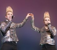 Jedward performing together on stage with silver jackets