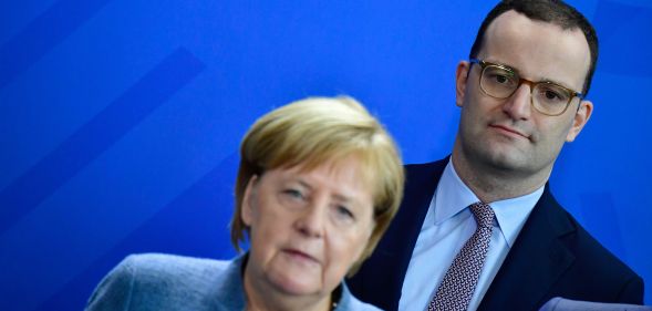 German Health Minister Jens Spahn stands behind Chancellor Angela Merkel