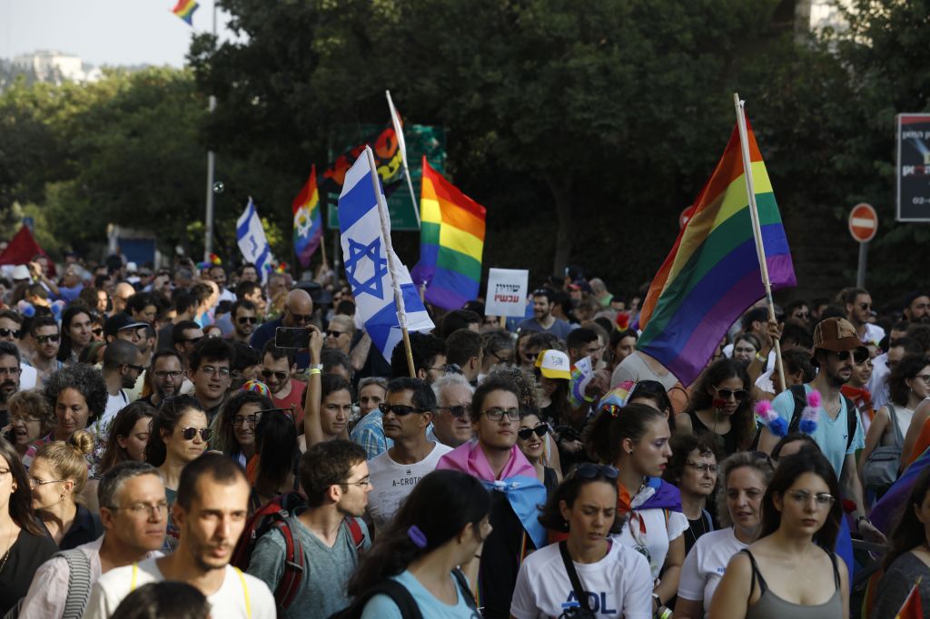 Participants wave Israeli and LGBT pride rainbow flags during Jerusalem's annual Gay Pride parade on August 2, 2018.