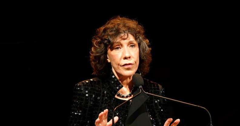 Lily Tomlin in a black sequinned jacket speaking into a microphone