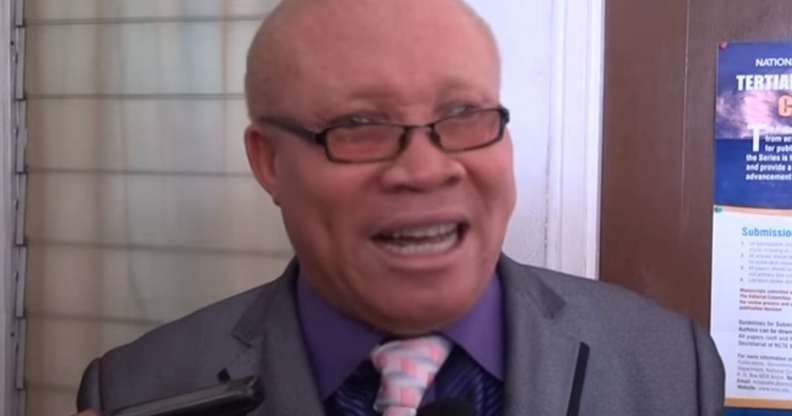 Moses Foh-Amoaning in a purple shirt and grey blazer talking to the camera